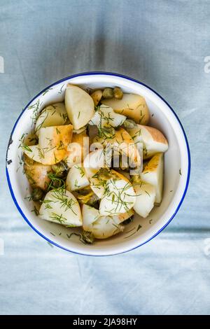 Salade de pommes de terre avec aneth et olives dans un bol sur fond bleu. Aliments sains, légumes et recettes maigres. Banque D'Images