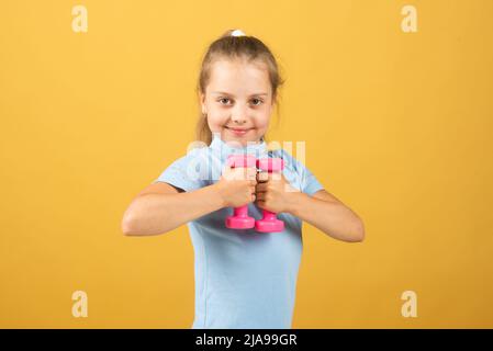 Enfant sportif avec haltères. Sport et fitness, santé et énergie pour les enfants. Un mode de vie sain pour les enfants. Gai garçon faire des exercices avec des haltères. Fille Banque D'Images