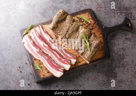 Bacon du ventre de porc sec aux épices et au romarin sur une planche en bois sur la table. Vue horizontale du dessus Banque D'Images