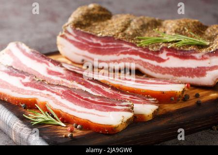 Bacon du ventre de porc sec aux épices et au romarin sur une planche en bois sur la table. Horizontal Banque D'Images