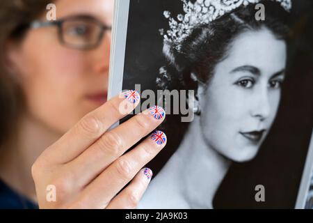 Fan avec les ongles peints avec le drapeau britannique tenant une copie du magazine OK avec un portrait d'une jeune Elizabeth II Jubilé de platine juin 2022 Banque D'Images