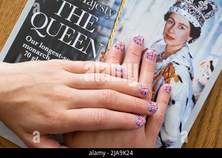 Femme aux ongles peints avec le drapeau britannique reposant sur le magazine OK avec une photo de la reine's Coronation. Jubilé de platine juin 2022 Banque D'Images