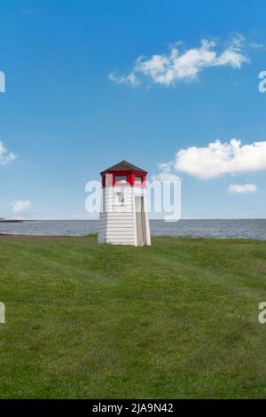 Petit phare de toit blanc et rouge près de l'océan sur herbe verte avec ciel bleu et nuages blancs. Paysage de Cape Cod. Copier l'espace Banque D'Images