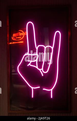 Symbole main de roche au néon rose avec le logo Hard Rock café reflété. Newcastle upon Tyne, Royaume-Uni. Banque D'Images