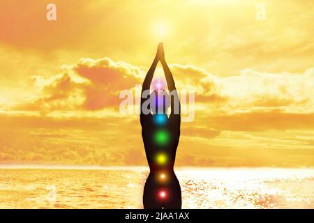 Chakras. Silhouette d'une femme avec les mains vers le haut sur le fond de la mer et du soleil. Concept d'harmonie Banque D'Images