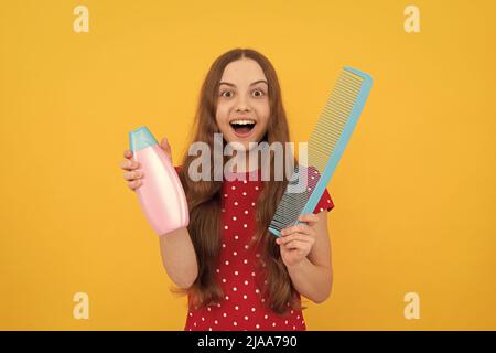 surprise teen fille a de longs cheveux tenir brosse et lotion, foyer sélectif, habitude quotidienne. Banque D'Images