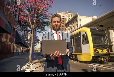 un homme freelance publie un blog en ligne sur un pc en extérieur, professionnel Banque D'Images