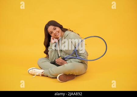 bonne enfance. enfant dans les vêtements de sport tenir raquette. enfant avec raquette. jeune fille se détendre après le sport Banque D'Images