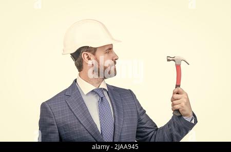 homme d'affaires confiant en costume et casque de sécurité tenir le marteau isolé sur blanc, affaires de sécurité Banque D'Images