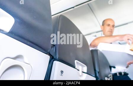 Préposé de vol servant repas et boissons aux passagers assis sur une chaise dans une cabine d'avion Airbus A319 exploité par Air France Banque D'Images