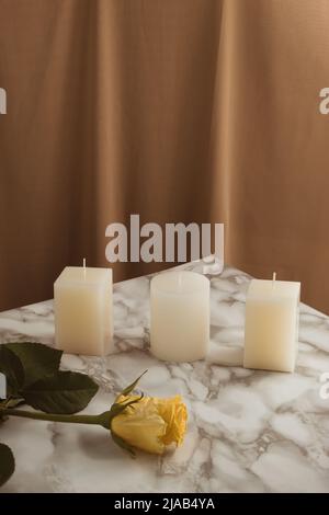 Composition romantique avec bougies et fleur rose jaune sur table en marbre. Arrière-plan de rideau beige vintage. Concept de la Saint-Valentin. Banque D'Images
