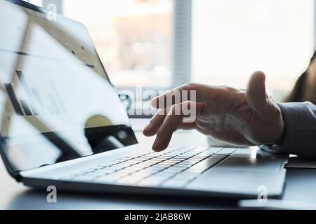 Gros plan de la main mâle appuyant sur la touche de l'ordinateur portable avec les données à l'écran, espace de copie Banque D'Images