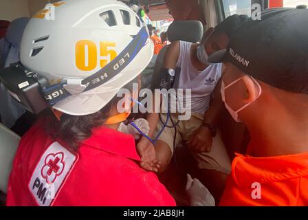 Banjarmasin. 29th mai 2022. La photo du téléphone portable prise le 29 mai 2022 montre des professionnels de la santé qui vérifient l'état physique d'un homme secouru dans une ambulance au port de Trisakti à Banjarmasin, au sud de Kalimantan, en Indonésie. Les sauveteurs ont déployé un hélicoptère et plusieurs navires avec plus de 100 personnes dans une opération de recherche et sauvetage pour 25 personnes disparues après qu'un navire a coulé dans l'eau au large de la province de Sulawesi Sud en Indonésie, a déclaré un secouriste dimanche. Credit: Bahaudin Quusairi/Xinhua/Alay Live News Banque D'Images