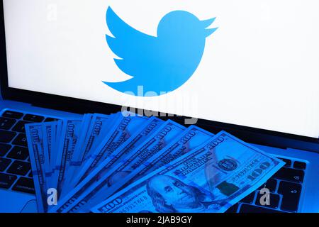 Billets de banque allumés avec une lumière bleue placée sur l'ordinateur portable avec logo Twitter flou. Concept. Stafford, Royaume-Uni, 29 mai 2022 Banque D'Images