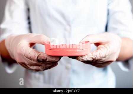 Modèle de mâchoire de retenue de dentiste à dent unique. Perte de dents, extraction, remplacement par des dents permanentes. Mauvaise hygiène buccale, caries, maladie parodontale, blessure. Médecin mains dans des gants. Photo de haute qualité Banque D'Images