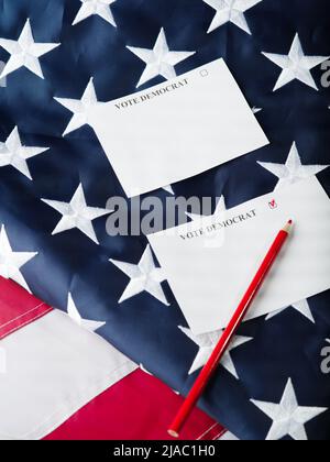 Élections aux États-Unis. Dans le contexte du drapeau américain, deux bulletins de vote ont été déposés : pour un démocrate, pour un républicain et pour un crayon rouge. Gratuit Banque D'Images