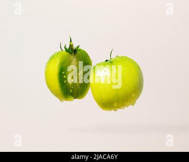 Tomates vertes non mûres coupées en deux sur fond gris. Concept de nourriture minimale. Banque D'Images