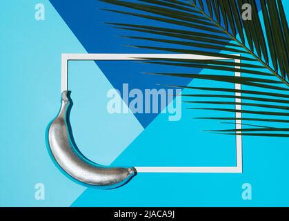 Banane peinte en argent sur trois arrière-plans bleus différents. Concept de fruits d'été avec palmier tropical et cadre. Pose à plat. Banque D'Images