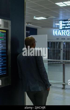 Homme décontracté appuyé contre le mur, attendant les arrivées à l'aéroport international de Manchester, Grand Manchester, Royaume-Uni. Banque D'Images