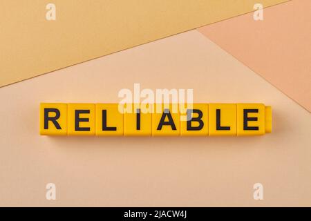 Le mot fiable écrit sur les cubes jaunes gros plan. Qualité ou performances constantes. Être digne de confiance. Banque D'Images