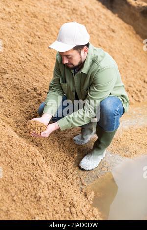 Les jeunes agriculteurs qui vérifient la qualité des brasseurs ont dépensé des grains en entreposage ouvert Banque D'Images