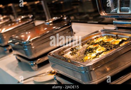 Le petit-déjeuner buffet est servi sur les plateaux chauffants du restaurant de l'hôtel, avec des œufs et des épinards Banque D'Images