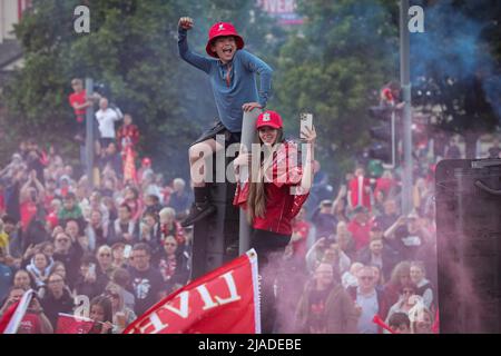 Les supporters grimpent sur un feu de circulation alors que l'équipe du FC Liverpool célèbre lors de la parade en bus à toit ouvert à travers la ville Banque D'Images