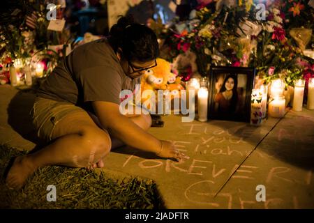 Uvalde, Texas, États-Unis. 28th mai 2022. Kandace Moralez, 26 ans, d'Uvalde, Texas, écrit, « Je t'aime Eliahna, toujours ma fille elle », devant une croix commémorative pour sa cousine Eliahna Torres, 10 ans, sur la place de la ville d'Uvalde, le samedi 28 mai 2022. Torres, un étudiant de l'école élémentaire Robb à Uvalde, est l'une des 21 victimes du massacre de l'école élémentaire Robb le mardi 24 mai 2022, au cours duquel le tireur Salvador Ramos, âgé de 18 ans, a tué 19 enfants et deux enseignants. (Credit image: © Jintak Han/ZUMA Press Wire) Banque D'Images