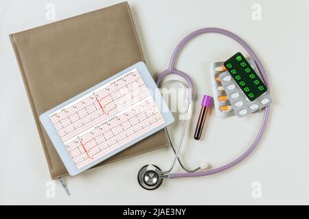 Un rapport cardiaque analyse l'électrocardiogramme vu sur un comprimé numérique avec un stéthoscope Banque D'Images