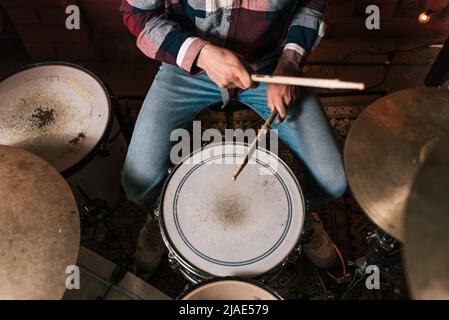 De plus de crop musicien anonyme avec des pilons de tambour jouant sur le jeu de tambour pendant la performance musicale en direct Banque D'Images