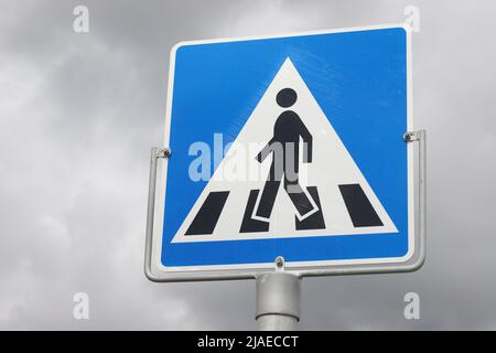 Vue à angle bas d'un panneau routier norvégien traversant un piéton contre le ciel clody. Banque D'Images