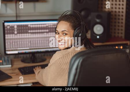 Joyeuse jeune femme africaine américaine musicienne, compositrice, ingénieur du son travaillant dans le studio d'enregistrement de musique Banque D'Images