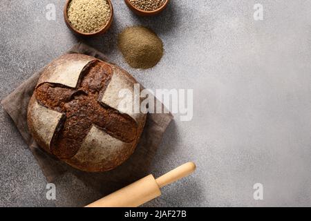 Pain de chanvre, graines, grains de chanvre, farine sur fond gris avec espace de copie. Pain de levain fraîchement cuit. Vue de dessus. Banque D'Images