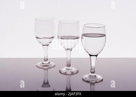 Trois verres à vin remplis d'eau réfléchie sur la table Banque D'Images