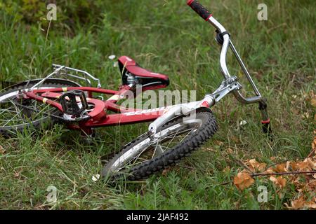 Le vélo rouge est couché sur l'herbe verte dans le parc ou dans le jardin. Fatigué des sports et des activités de plein air Banque D'Images