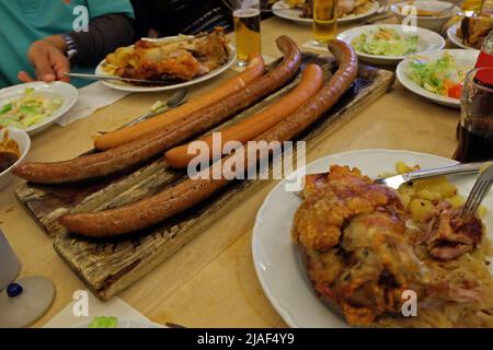 Gros plan sur les saucisses allemandes et les cuisses de porc frite servies avec de la bière glacée, de la salade de coleslaw et des sauces à trempette variées Banque D'Images