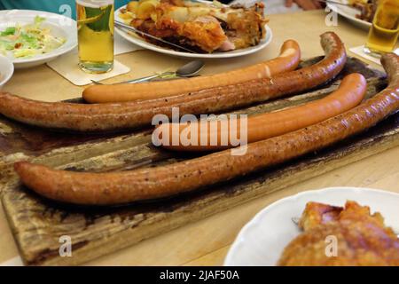 Gros plan sur les saucisses allemandes et les cuisses de porc frite servies avec de la bière glacée, de la salade de coleslaw et des sauces à trempette variées Banque D'Images