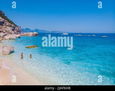 Golfo di Orosei Sardina, hommes et femmes sur la plage Sardaigne Italie, jeune couple vacances Sardaigne Italie, couple hommes et femme jouant dans l'océan avec l'eau bleu clair en Italie Banque D'Images