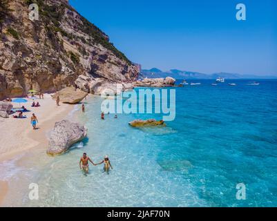 Golfo di Orosei Sardina, hommes et femmes sur la plage Sardaigne Italie, jeune couple vacances Sardaigne Italie, couple hommes et femme jouant dans l'océan avec l'eau bleu clair en Italie Banque D'Images