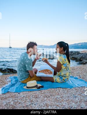 Golfo di Orosei Sardina, hommes et femmes sur la plage manger de la pizza, hommes et femmes heureux sur la plage avec pizza en Italie. Banque D'Images