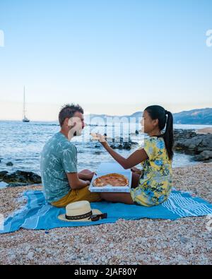 Golfo di Orosei Sardina, hommes et femmes sur la plage manger de la pizza, hommes et femmes heureux sur la plage avec pizza en Italie. Banque D'Images