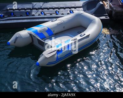 Un bateau à moteur gonflable gris-bleu est amarré dans la baie de mer avec de l'eau brillante Banque D'Images