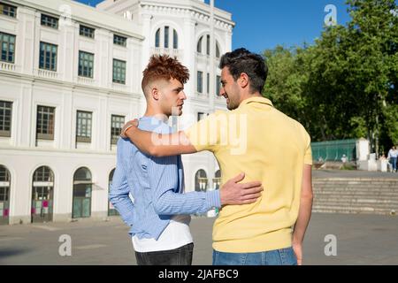 Vue de dos couple hommes gays embrassé regardant l'un l'autre avec le symbole de fierté gay en plein air. concept de relation lgbt Banque D'Images