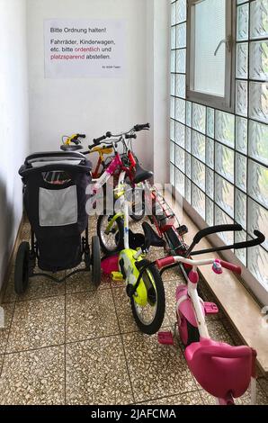 Couloir encombré de landaus et de vélos pour enfants, une affiche demande instamment, Allemagne Banque D'Images