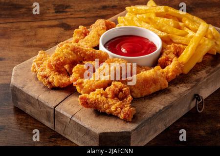 Filets de poulet, nuggets panés, sauce barbecue et frites, sur fond de bois Banque D'Images