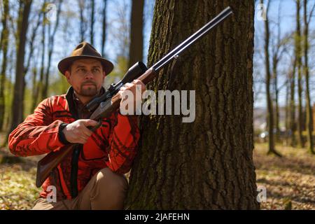 Chasseur avec fusil en attente de proie dans la forêt. Banque D'Images