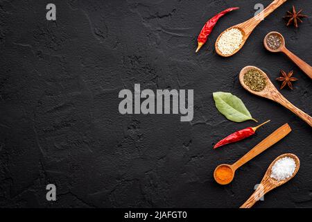 Variété d'épices et d'herbes colorées en cuillères en bois sur la table de cuisine, vue sur le dessus Banque D'Images
