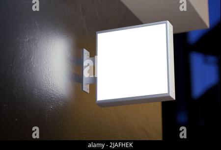 Affiche murale lumineuse maquette accrochée à la façade d'un magasin la nuit. Modèle de signalisation vierge pour le marquage dans un rendu réaliste 3D Banque D'Images