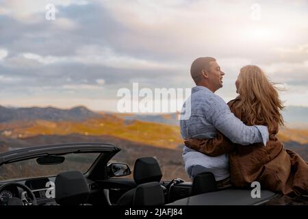 Vue arrière d'un couple heureux souriant embrassant et riant ensemble à l'extérieur pendant le voyage Banque D'Images