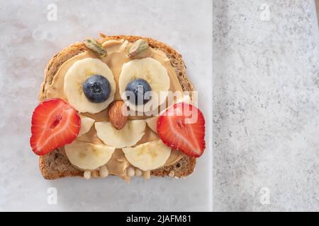 Pain grillé pour le petit-déjeuner des enfants avec tartiner au beurre d'arachide, banane et fraise Banque D'Images